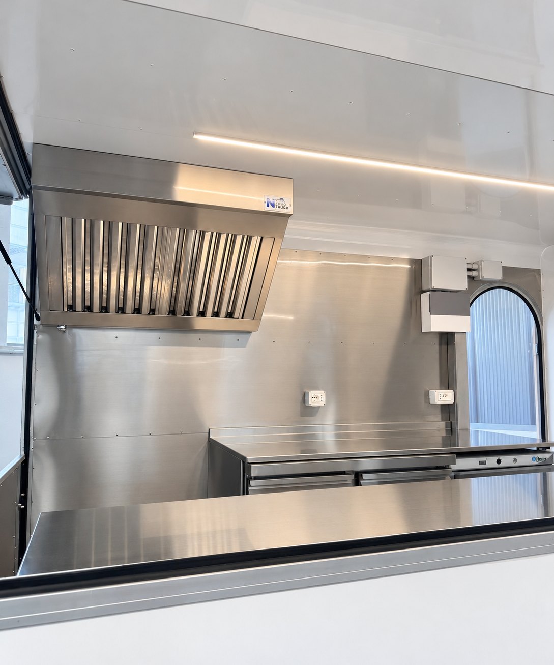 Interno del rimorchio: cappa aspirante, banco refrigerato e tavolo di lavoro