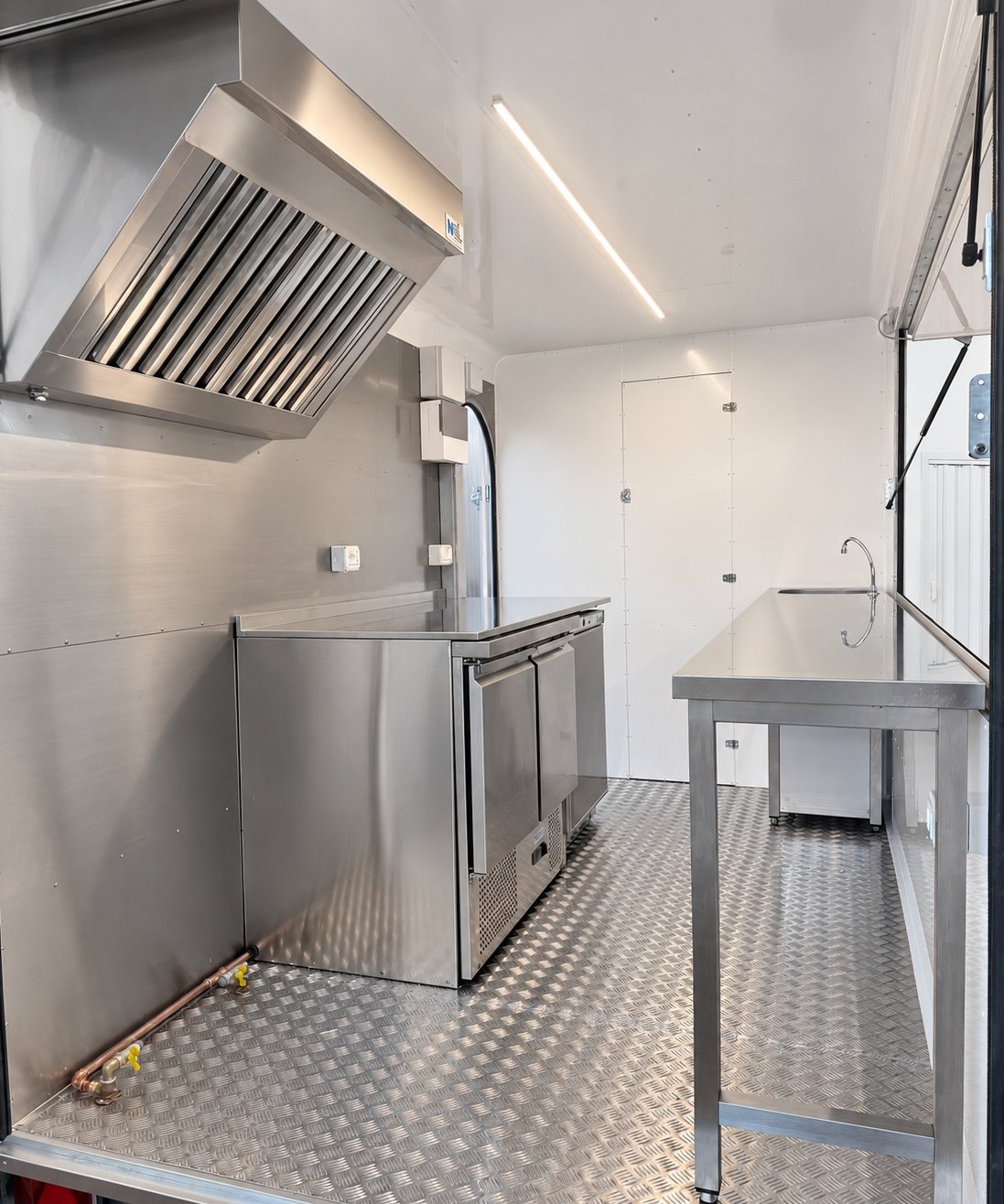Interno del rimorchio: parete cottura in acciaio inox con cappa